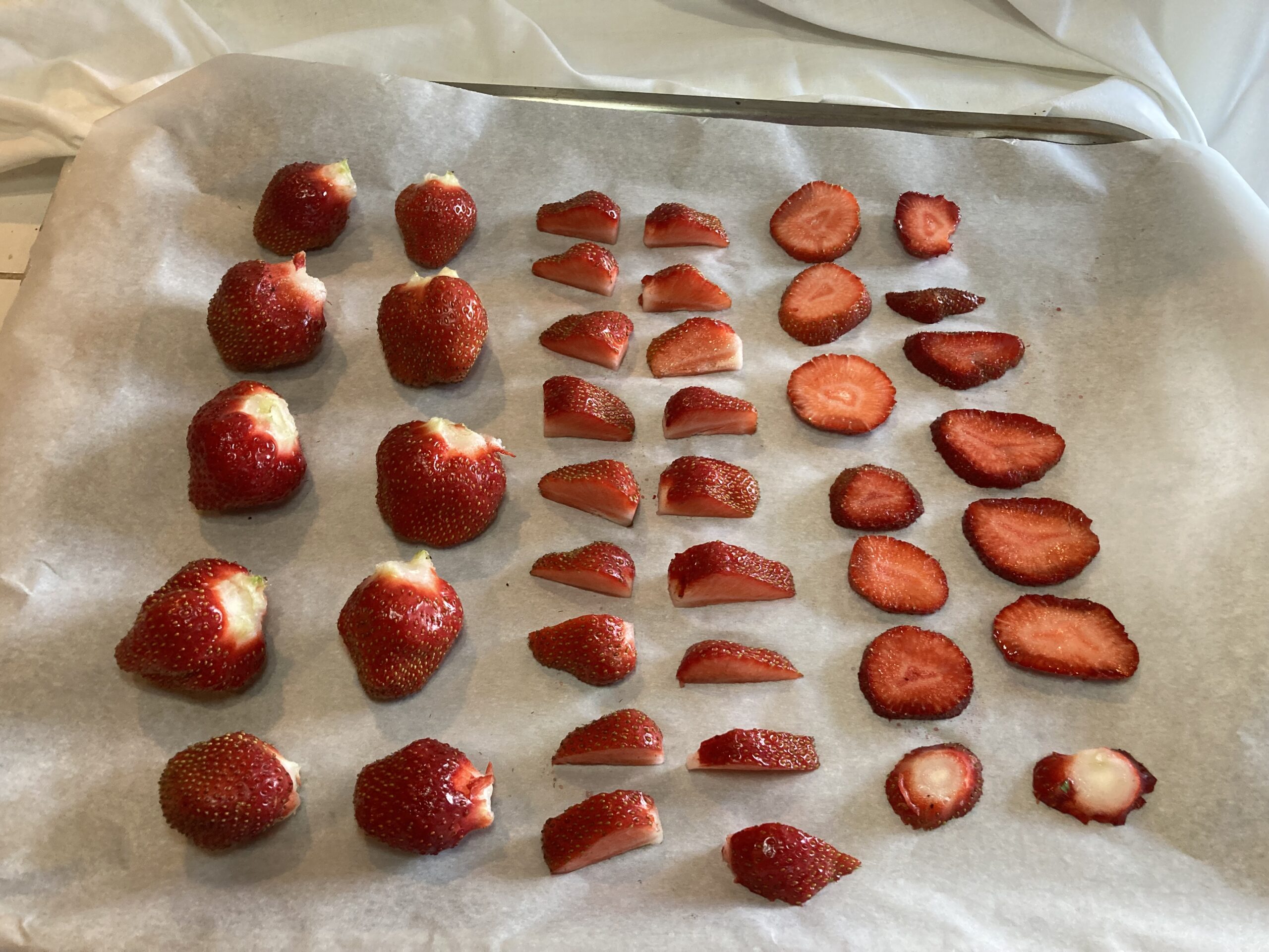 Cut and whole strawberries on a parchment lined tray